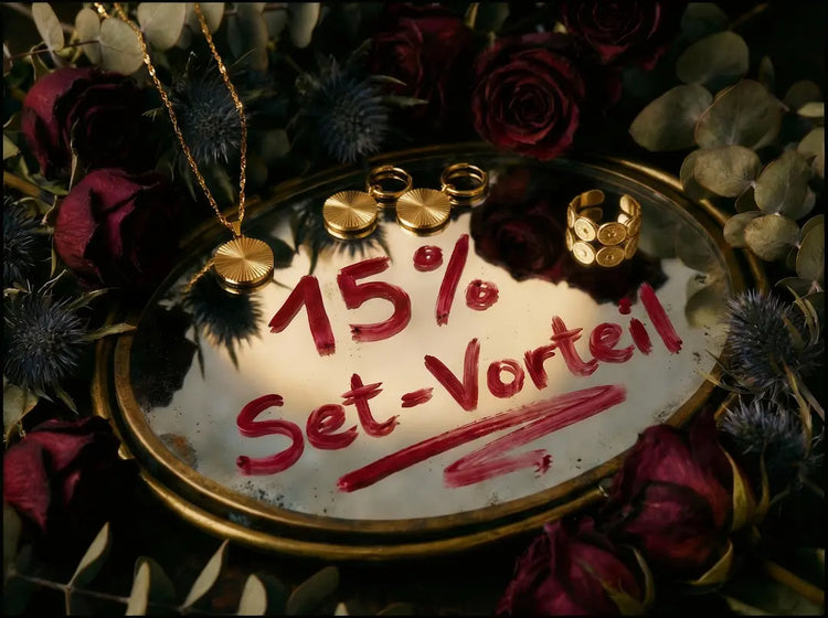ERCY'S Set-Vorteil bei bymercy.de: Goldener Schmuck auf einem Spiegel mit der Aufschrift 15 % Set-Vorteil, umrahmt von dunklen Rosen.