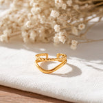 Chevron-Ring aus Edelstahl 18 K vergoldet, offen und verstellbar, mit gedrehter Struktur auf hellem Stoff und Trockenblumen im Hintergrund – Soriel Ring | Mercy’s Jewelry