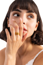 Damen-Ring Kelana – Edelstahl 18K vergoldet, breiter mehrreihiger Ring, frontal am Finger getragen mit Hand am Gesicht