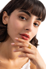 Damen-Ring Nirella – Edelstahl 18K vergoldet, breiter mehrreihiger Ring mit Rillen-Design, am Finger getragen mit Hand an Lippen