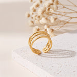 Dreireihiger Ring aus Edelstahl 18 K vergoldet, offen und verstellbar, mit strukturierter Oberfläche auf heller Steinplattform und Trockenblumen im Hintergrund – Alirae Ring | Mercy’s Jewelry