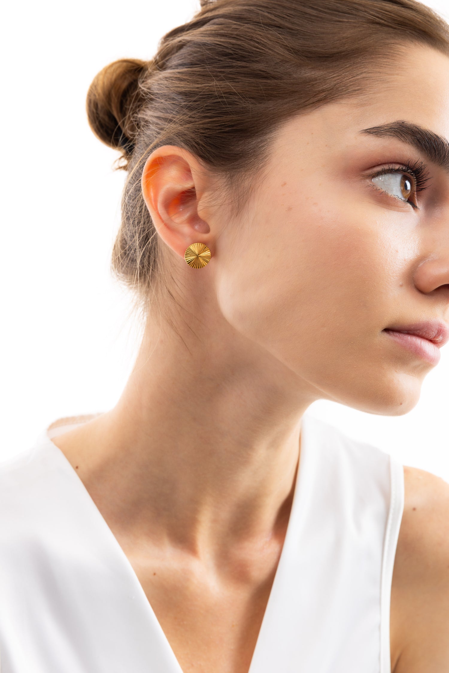 Model trägt die Elira Studs Ohrringe, goldene Ohrstecker mit Sonnenrelief aus Edelstahl, 18K vergoldet