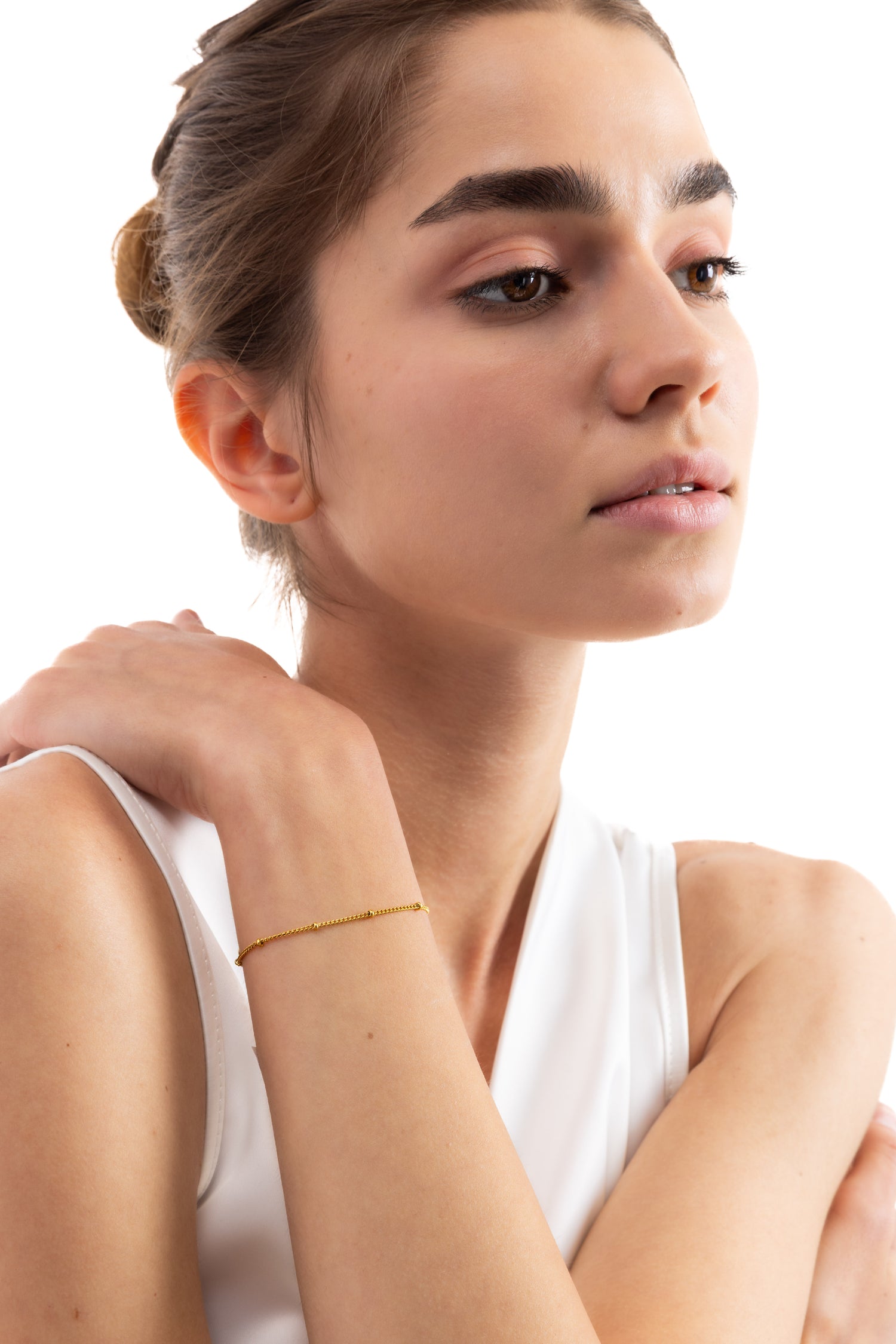 Modell trägt das Enira Armband mit Goldkügelchen als filigranes Gliederarmband aus Edelstahl 18K vergoldet in Frontansicht