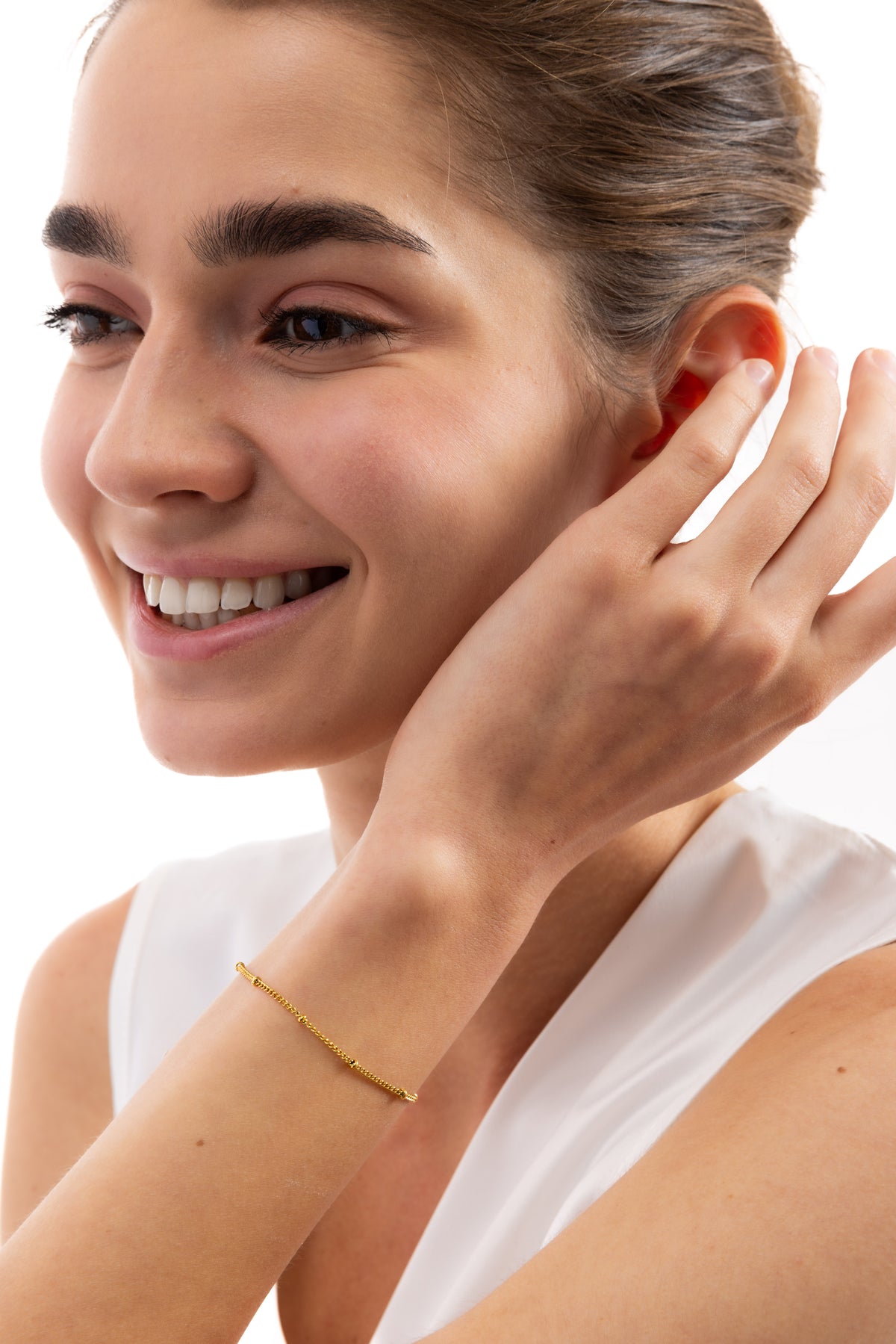Enira Armband mit Goldkügelchen aus Edelstahl 18K vergoldet, am Handgelenk getragen, Modell lächelt