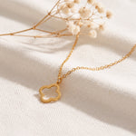 Feine Kleeblatt-Halskette aus Edelstahl 18 K vergoldet, liegt auf hellem Stoff mit Trockenblumen im Hintergrund – Thaleya Halskette | Mercy’s Jewelry