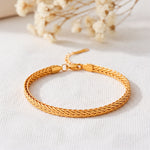 Geflochtenes Armband aus Edelstahl 18 K vergoldet mit dichter Kettenstruktur, elegant auf hellem Stoff mit Trockenblumen – Kaelwyn Armband | Mercy’s Jewelry