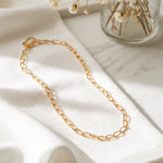 Goldene Gliederkette aus Edelstahl 18K vergoldet, liegt auf weißem Stoff mit getrockneten Blumen im Hintergrund – Marva Necklace | Mercy’s Jewelry