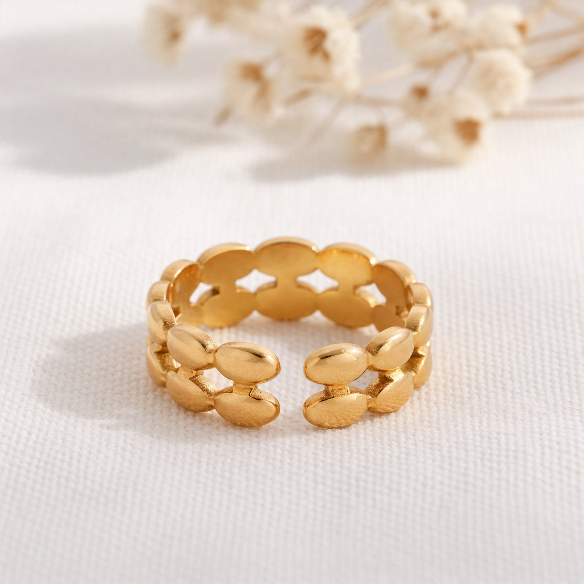 Gliederring aus Edelstahl 18 K vergoldet, offen und verstellbar, mit ovalen Glied-Elementen auf hellem Stoff und Trockenblumen im Hintergrund – Seraya Ring | Mercy’s Jewelry