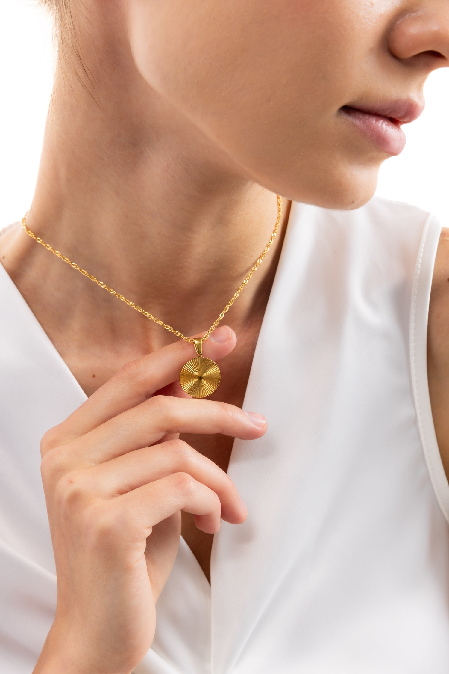 Elira Kette von Mercy’s Jewelry – Edelstahl 18K vergoldet, Coin-Anhänger mit Sonnenmotiv, Nahaufnahme am Hals, zwischen Fingern gehalten