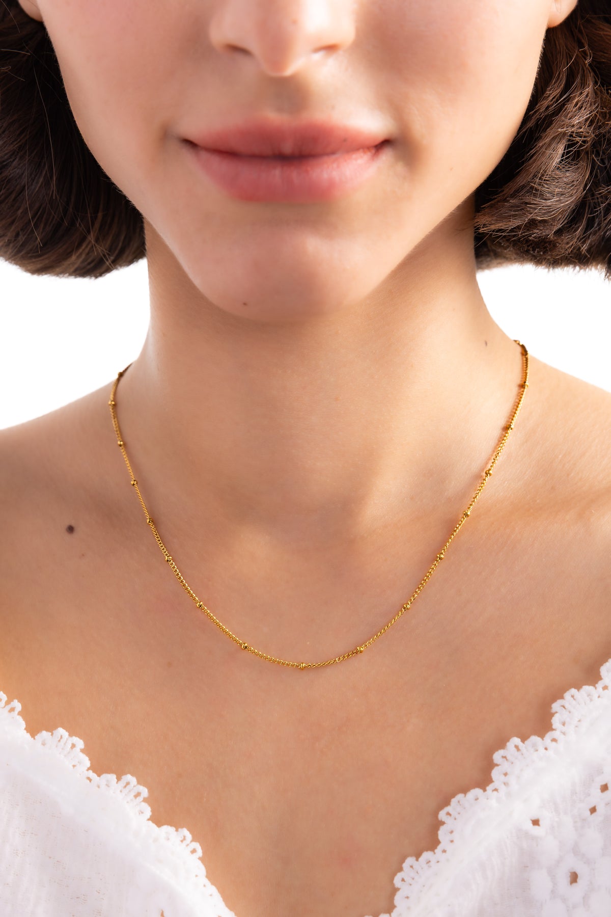 Enira Kette – Edelstahl 18K vergoldet, Gliederkette mit goldenen Kügelchen, frontal am Hals getragen, Nahaufnahme Dekolleté