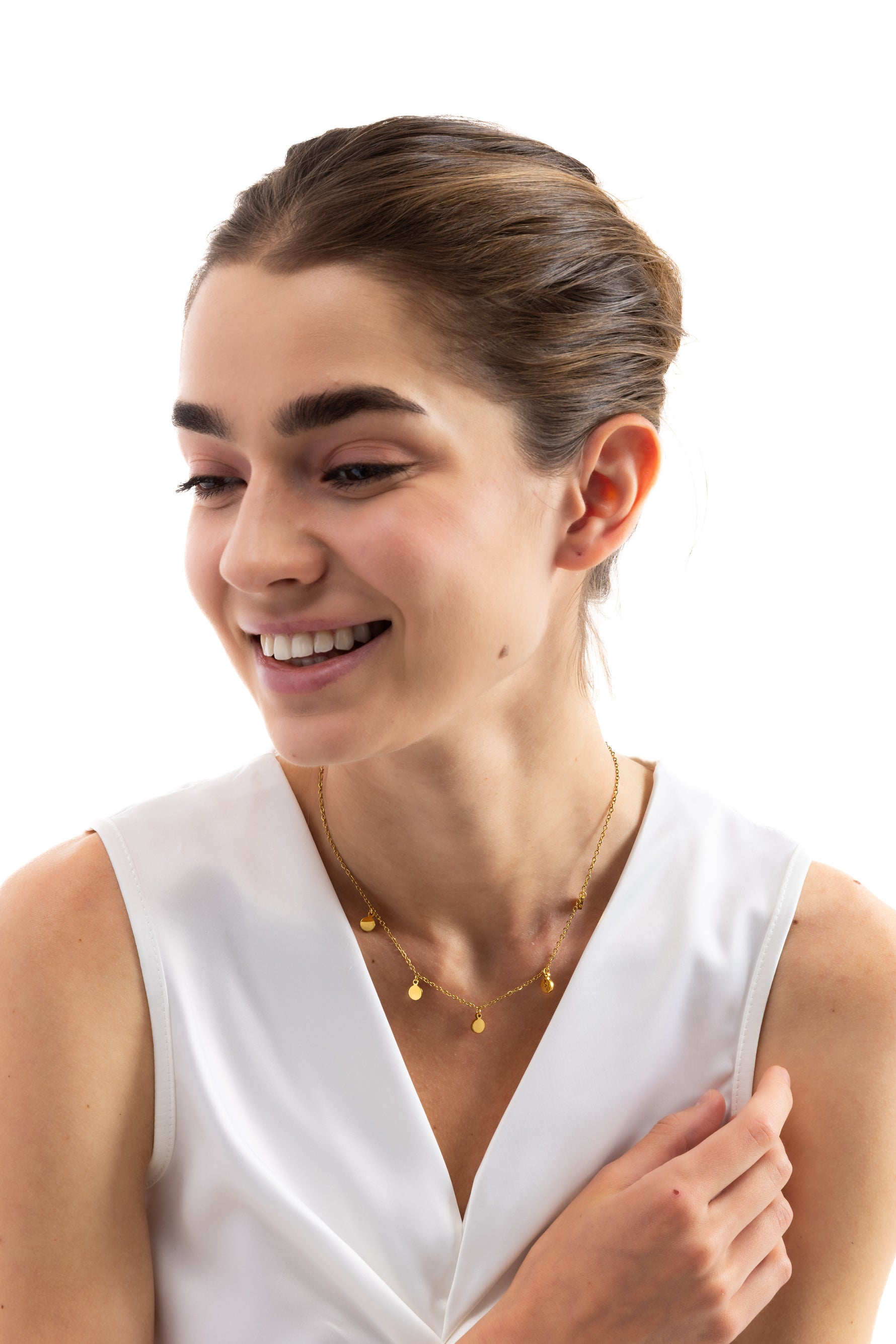 Kaira Kette – Edelstahl 18K vergoldet, goldene Plättchen-Kette, frontal am Hals getragen, Modell lächelt mit Hand am Hals