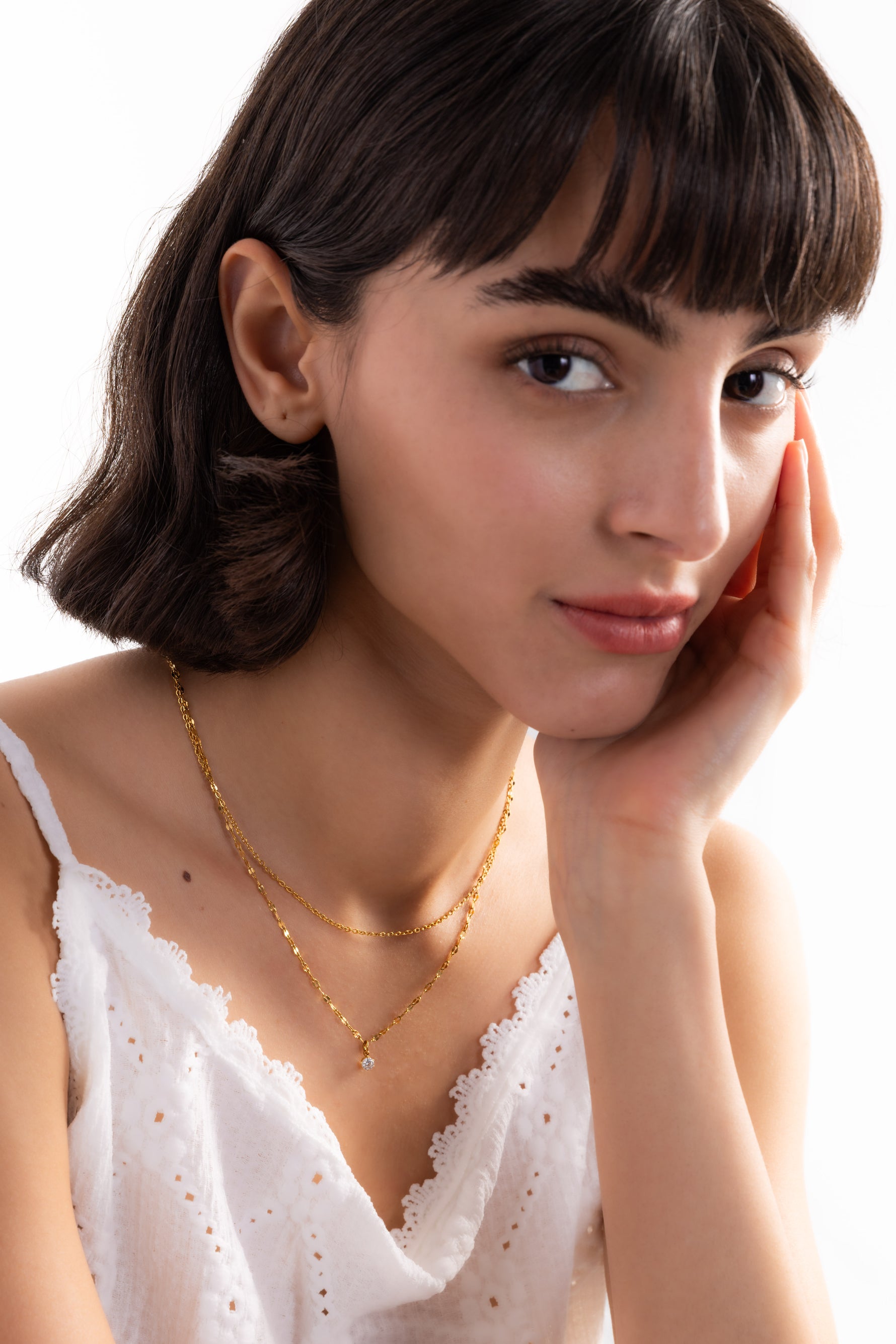 Lirae Halskette – Edelstahl 18K vergoldet, Layering-Kette mit Zirkonia-Anhänger, seitlich getragen, Hand berührt das Gesicht