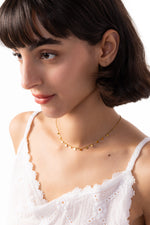 Lyra Kette – Edelstahl 18K vergoldet, elegante Plättchen-Kette, frontal am Hals getragen, Kopf leicht geneigt