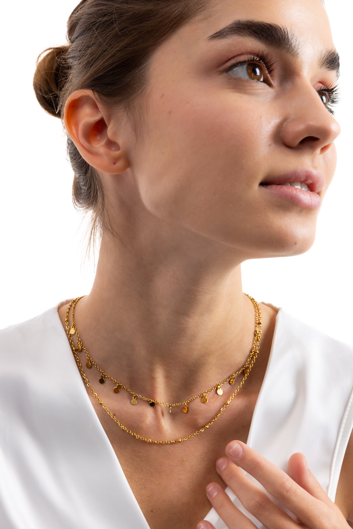 Naia Layers Kette – Edelstahl 18K vergoldet, zweireihige Kette mit Plättchen und Mini-Knoten, Nahaufnahme auf Brusthöhe