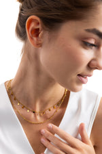 Naia Layers Kette – Edelstahl 18K vergoldet, Kette mit Plättchen und Mini-Knoten, seitlich getragen, Kopf geneigt