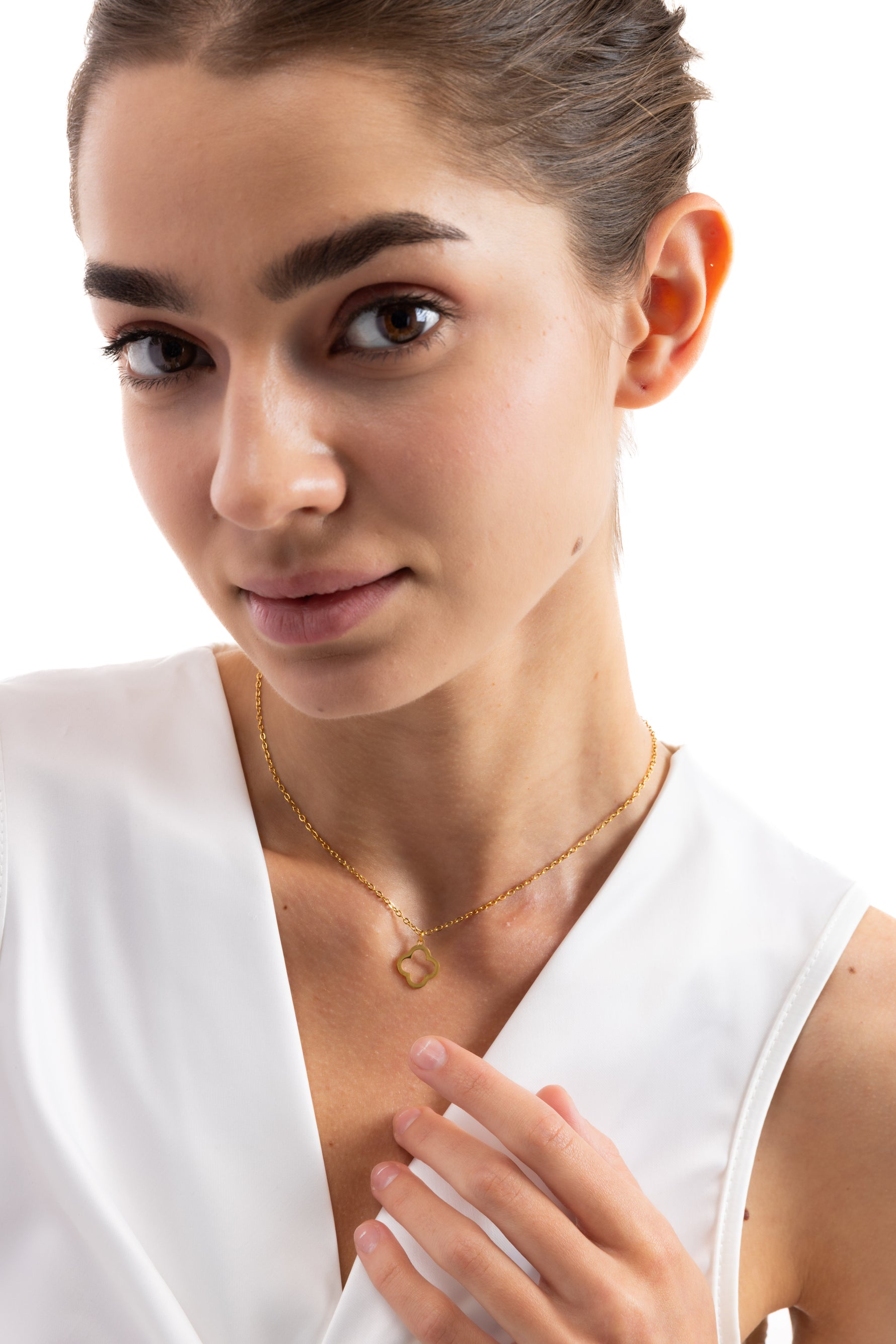 Thaleya Kette – Edelstahl 18K vergoldet, Kette mit stilisiertem Kleeblatt-Anhänger, Nahaufnahme, Hand berührt den Anhänger