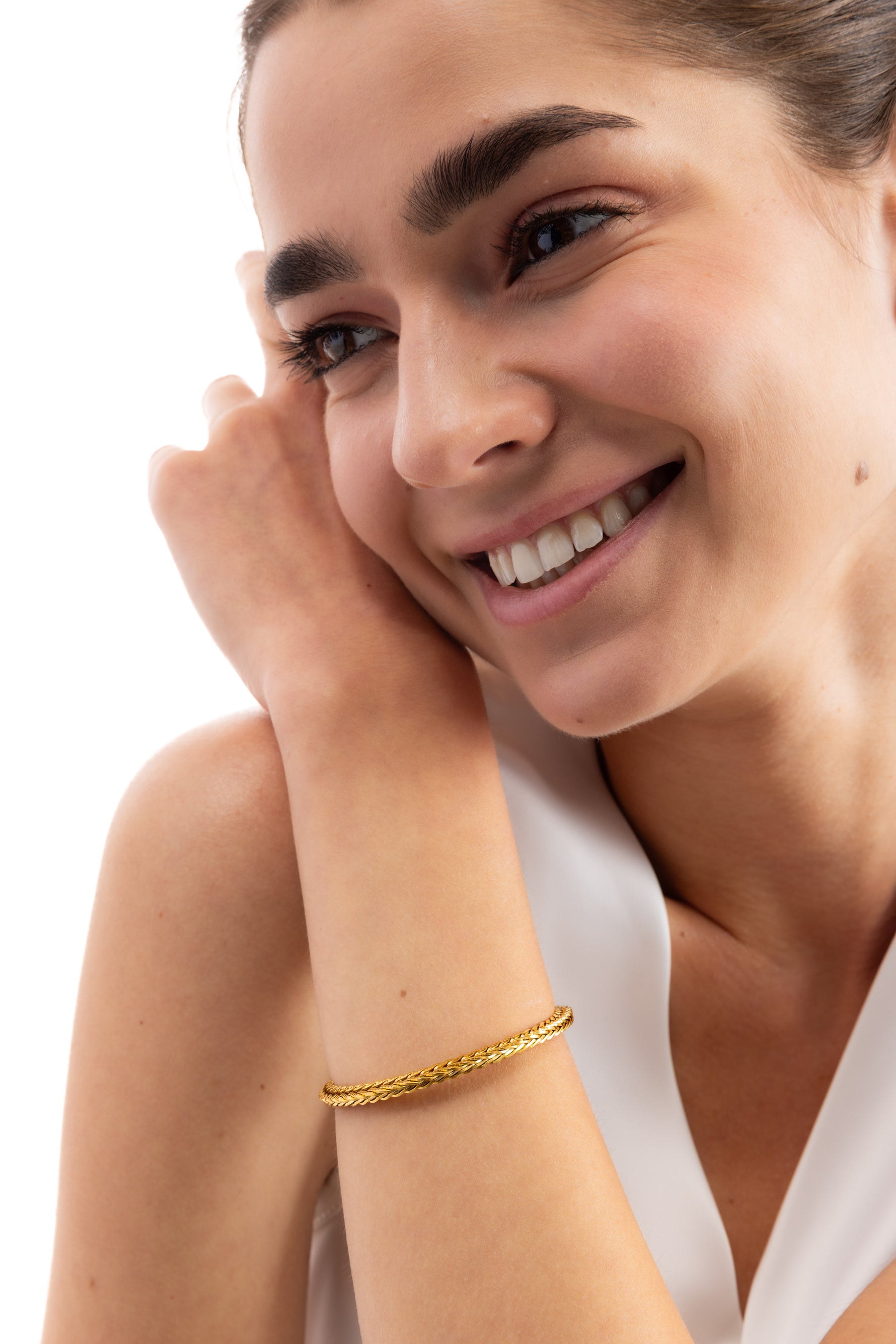 Kaelwyn Armband mit geflochtenen Gliedern, Edelstahl 18K vergoldet, Modell trägt das Armband lachend am Handgelenk