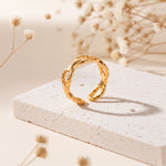 Kettenring aus Edelstahl 18 K vergoldet, offen und verstellbar, mit elegant gedrehten Gliedern auf heller Steinplattform mit Trockenblumen im Hintergrund – Talira Ring | Mercy’s Jewelry