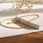 Kordel-Halskette aus Edelstahl 18 K vergoldet, liegt auf hellem Stoff und Holztisch mit Trockenblumen im Hintergrund – Solira Halskette | Mercy’s Jewelry