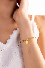 Lyssira Armband Edelstahl 18K vergoldet mit Goldkugeln, Nahaufnahme, Frau berührt ihren Hals, Armband am Handgelenk getragen