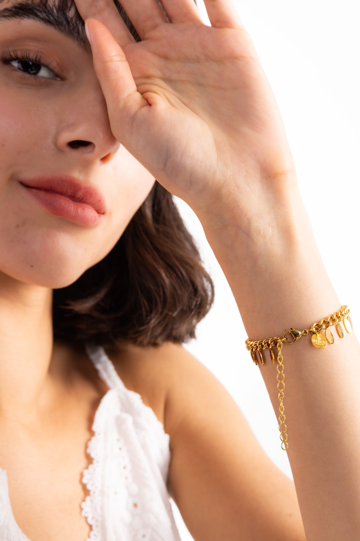 Marvella Armband aus Edelstahl 18K vergoldet mit Leaf-Charms, getragen am Handgelenk, Frau hebt Arm in eleganter Pose
