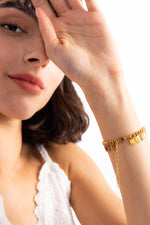 Marvella Armband aus Edelstahl 18K vergoldet mit Leaf-Charms, getragen am Handgelenk, Frau hebt Arm in eleganter Pose