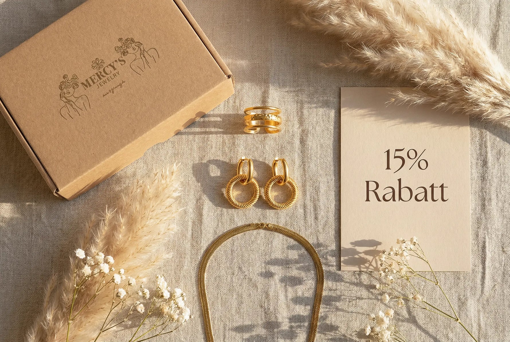 Mercy’s Jewelry Geschenkbox mit drei goldenen Schmuckstücken und einer Karte mit 15% Rabatt als hochwertiges Flatlay für den 3er-Deal.