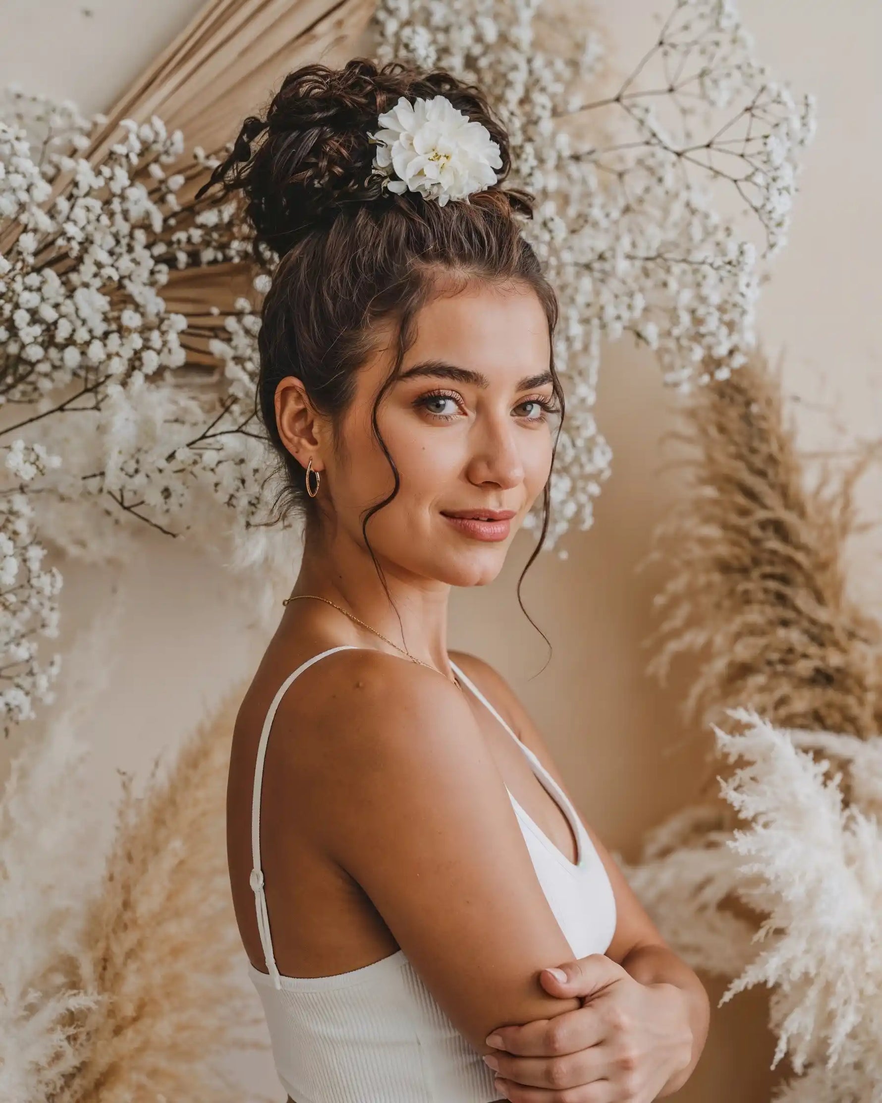 Model mit hochgesteckten Haaren trägt Mercy’s Jewelry Schmuck – goldene Creolen und feine Halskette vor Blumendeko