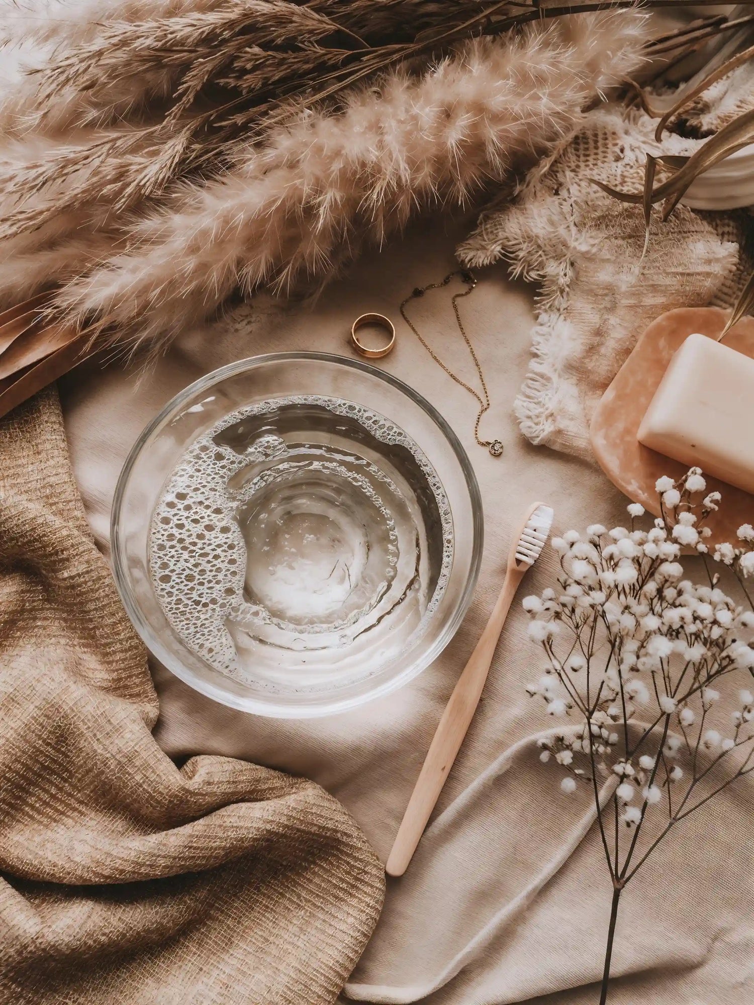 Glasschale mit Wasser, Schmuckstücken, Zahnbürste und Seife – Anleitung zur Schmuckpflege von Mercy’s Jewelry