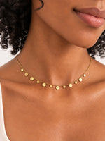 Lyra Plättchenkette in Gold am Hals getragen, mit feinen Kettengliedern und unterschiedlich großen runden Plättchen.