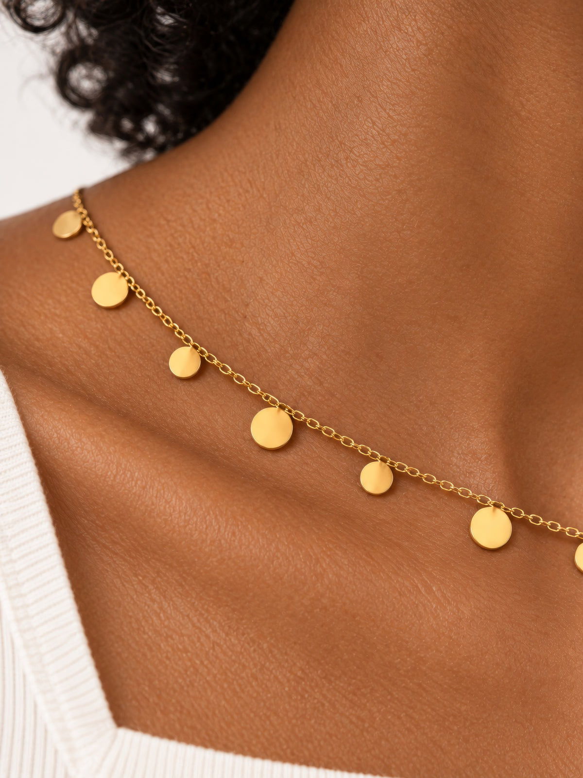 Detailaufnahme der Lyra Goldkette mit glatten, runden Plättchen und feinen ovalen Kettengliedern.