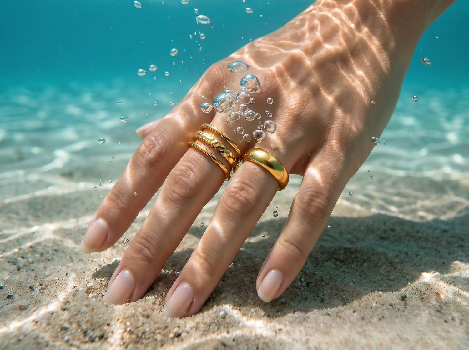 Goldene wasserfeste Ringe aus 316L Edelstahl von MERCY'S Jewelry an einer Hand unter Wasser


