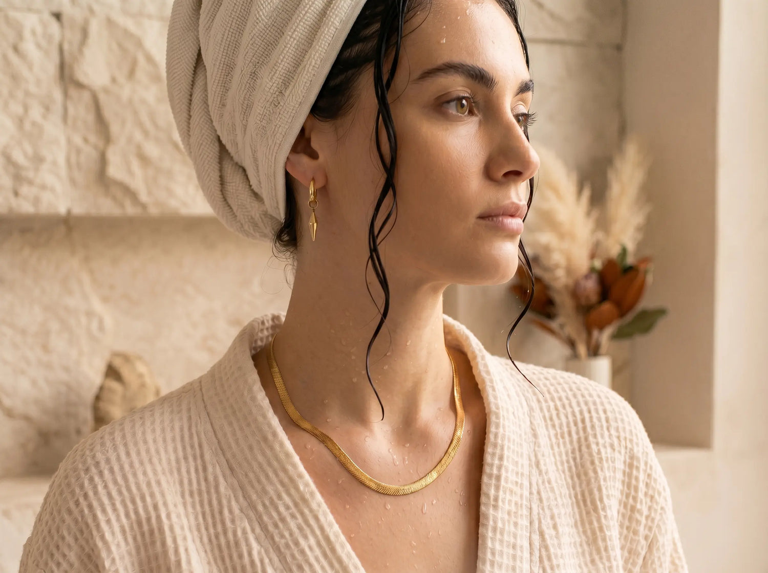 Frau im Bademantel nach der Dusche trägt wasserfeste goldene Kette und Ohrringe von MERCY'S Jewelry