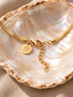 Karabinerverschluss der Velira-Schlangenkette mit Verlängerungskette und graviertem Mercy’s-Jewelry-Plättchen auf einer Muschel.
