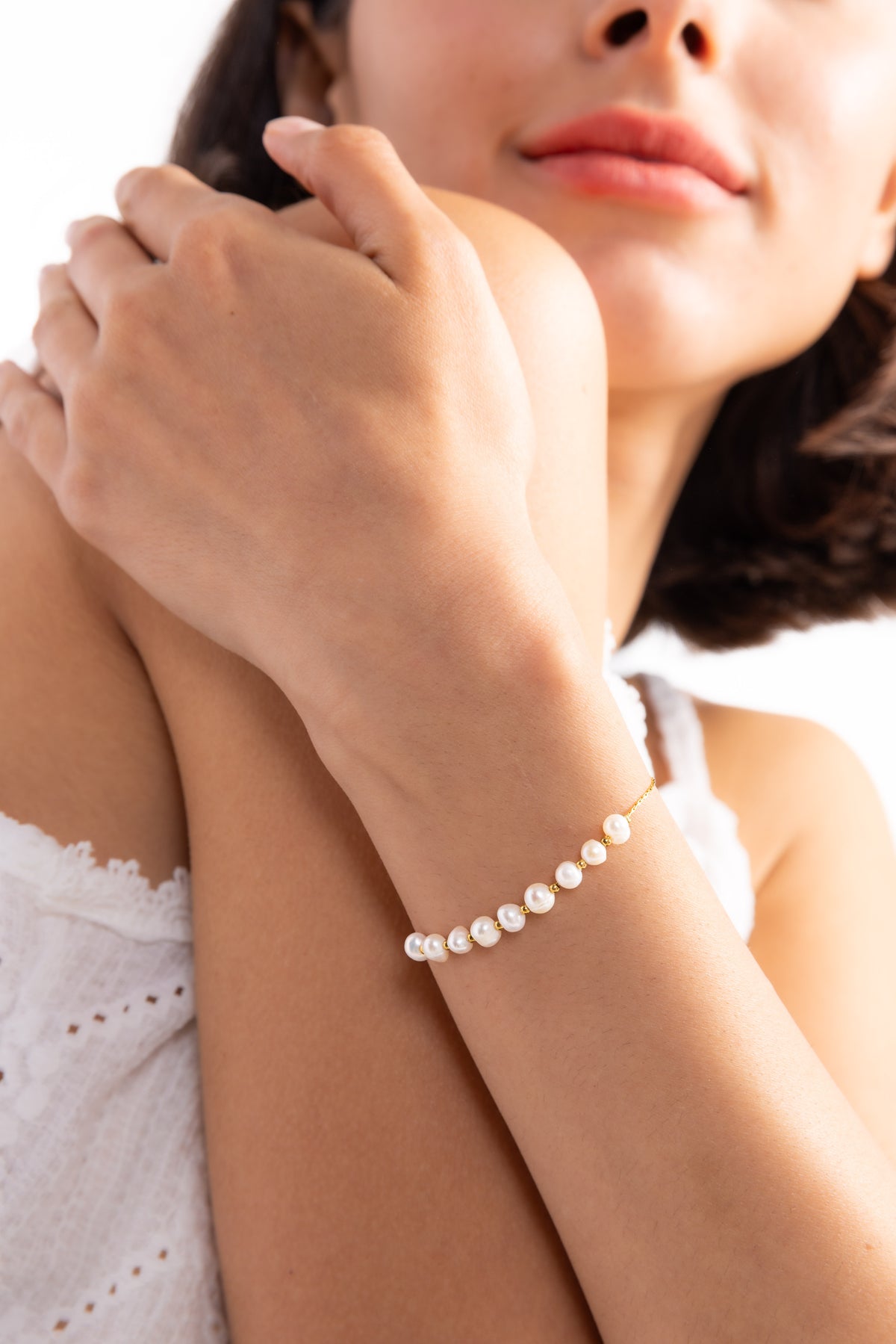 Noelia Armband mit Perlen aus Edelstahl 18K vergoldet, Modell verschränkt die Hände und zeigt das Armband dezent
