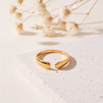 Offener Ring aus Edelstahl 18 K vergoldet, mit elegant geschwungener Tropfenform auf heller Steinplattform mit Trockenblumen im Hintergrund – Amelina Ring | Mercy’s Jewelry