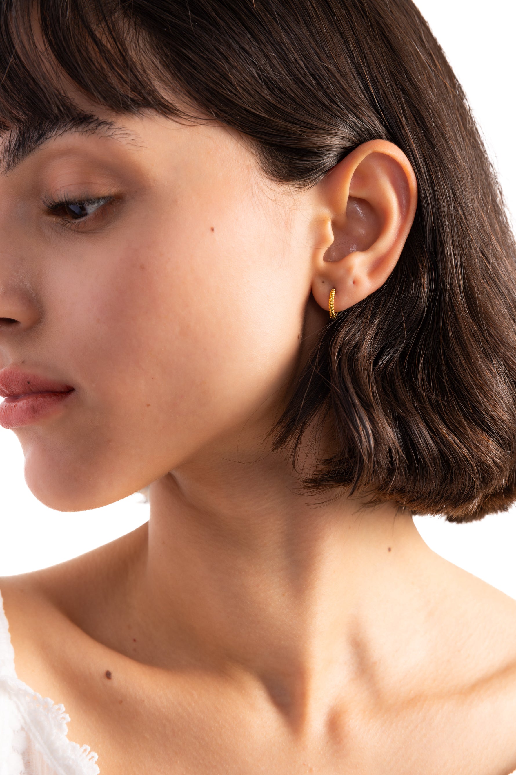 Avenil Huggies Edelstahl 18K vergoldet – Portraitaufnahme am Modell, strukturierte goldene Twist-Huggies für eleganten Look