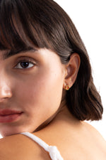 Enoa Studs Edelstahl 18K vergoldet – Portraitaufnahme am Modell, dezente goldene Ohrstecker in runder Form, schlicht und modern