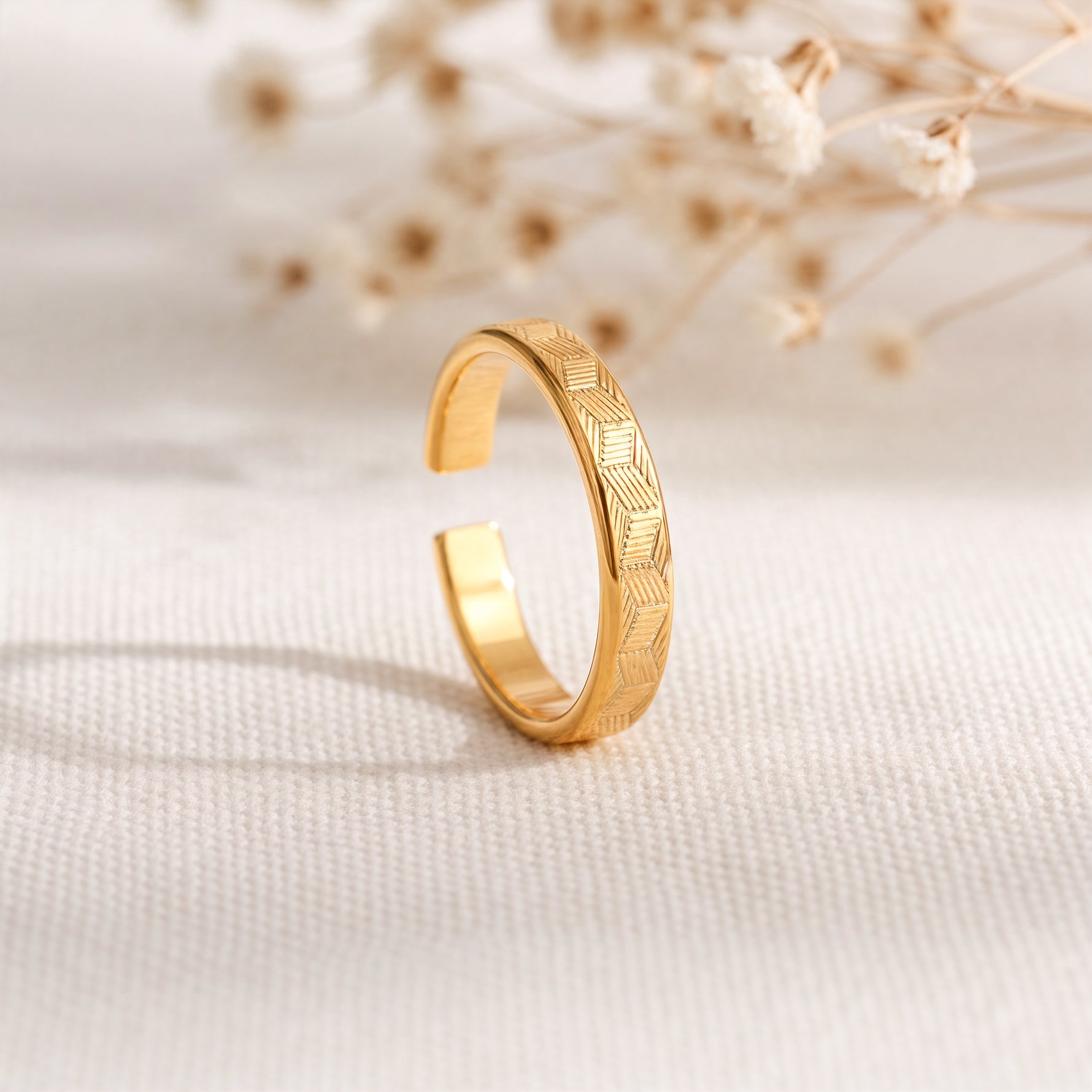 Ring aus Edelstahl 14 K vergoldet, offen und verstellbar, mit feiner Struktur auf hellem Stoff mit Trockenblumen im Hintergrund – Luneth Ring | Mercy’s Jewelry