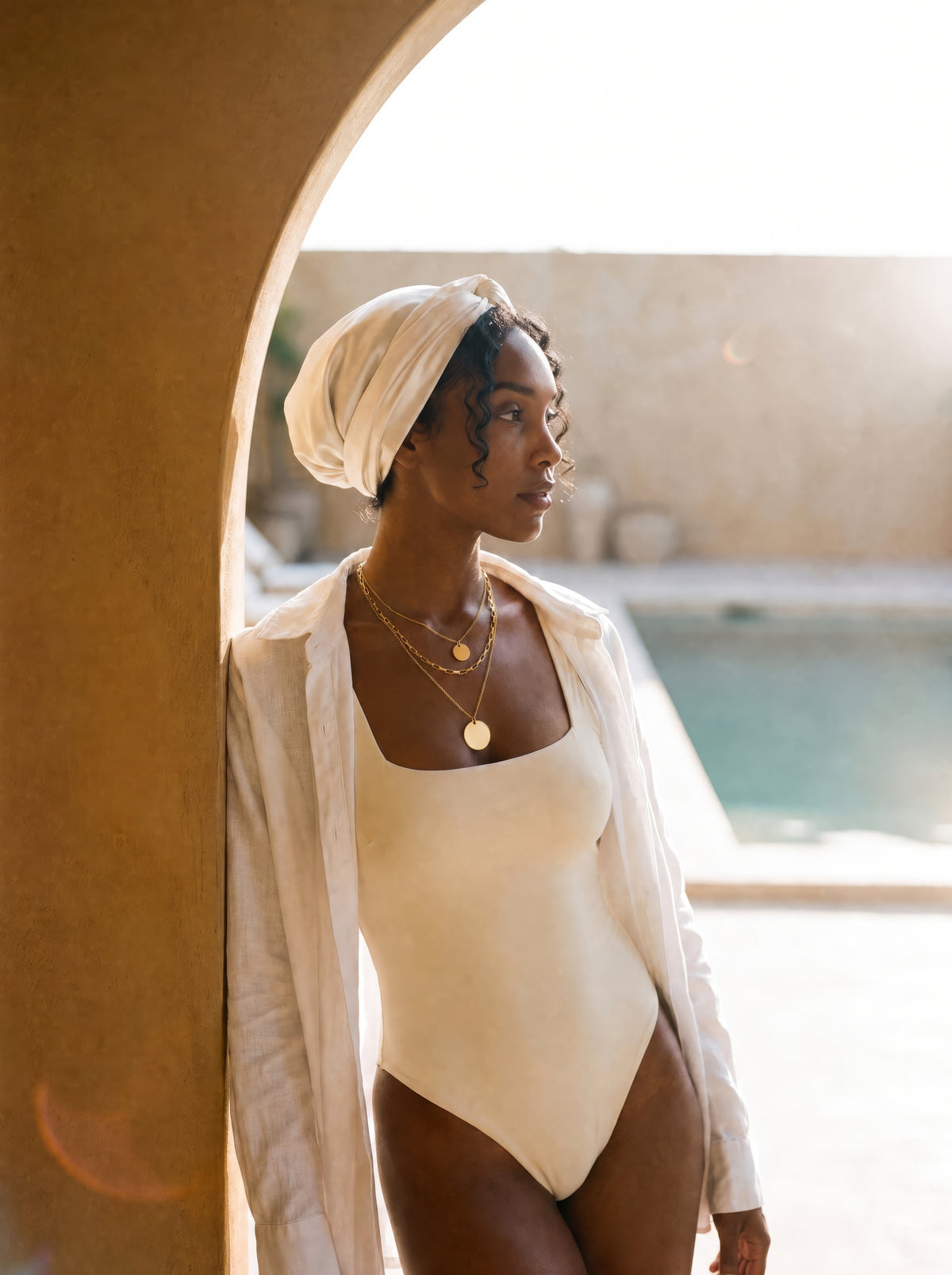 Frau trägt die dreilagige Sienna Layers Kette in Gold am Pool, Layering-Halskette aus wasserfestem Edelstahl