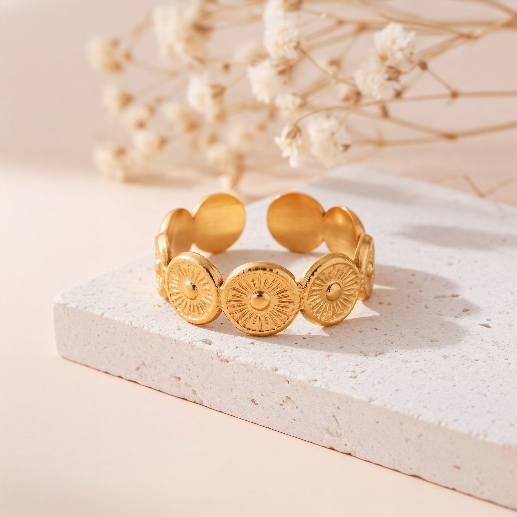 Statement-Ring aus Edelstahl 18 K vergoldet, offen und verstellbar, mit kreisförmigem Struktur-Design auf heller Steinplatte mit Trockenblumen – Aurema Ring | Mercy’s Jewelry