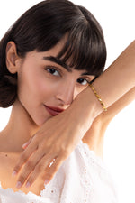 Talea Armband aus Titanium Steel 18K vergoldet, Frau legt den Arm mit dem Armband sanft an ihr Gesicht, dezente Nahaufnahme