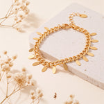 Vergoldetes Gliederarmband aus Edelstahl 18 K, mit ovalen Plättchen-Anhängerchen auf heller Steinplattform mit Trockenblumen – Marvella Armband | Mercy’s Jewelry