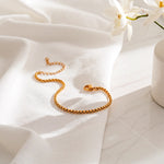 Zartes Armband aus Edelstahl 18 K vergoldet mit feiner Gliederstruktur, elegant auf weißem Stoff im Sonnenlicht drapiert – Amelira Armband | Mercy’s Jewelry