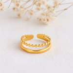 Zweireihiger Kugelring aus Edelstahl 18 K vergoldet, offen und verstellbar, mit polierter Oberfläche auf hellem Stoff und Trockenblumen im Hintergrund – Nayomi Ring | Mercy’s Jewelry